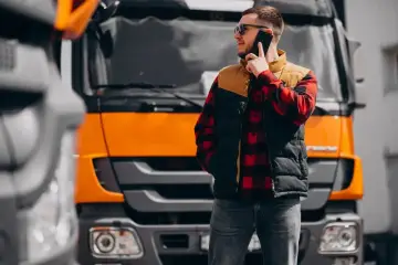 Kierowca tira rozmawia przez telefon, zastanawiając się, ile zarabiają kierowcy tirow.