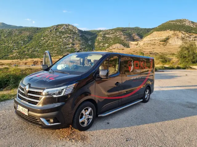Czarny bus OKL Travel Rent z napisem "Polska-Niemcy-Holandia" na tle gór. Chcesz wiedzieć, ile kosztuje bus do Niemiec? Sprawdź ofertę!